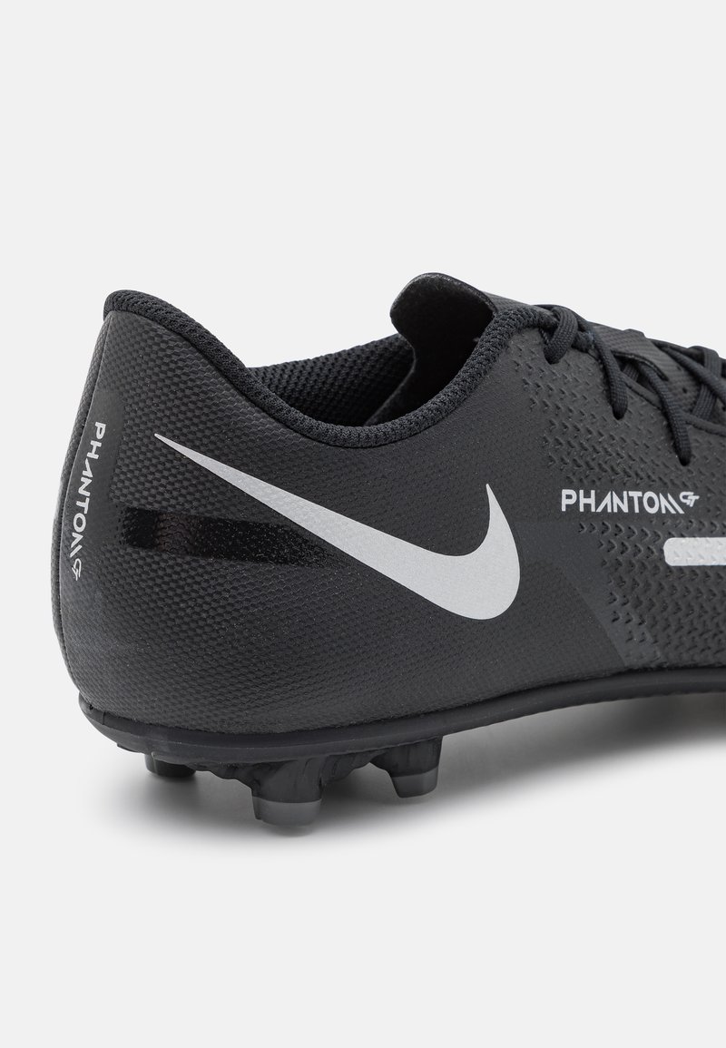 Botín deportivo negro con parte superior texturizada, que presenta un swoosh blanco de Nike y la marca "Phantom". Clavos de goma para tracción.