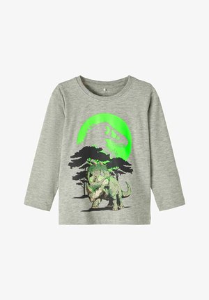 Camisa de manga larga gris con un diseño de dinosaurio en verde y negro, que presenta un triceratops y la silueta de un T-Rex contra árboles y un círculo verde.