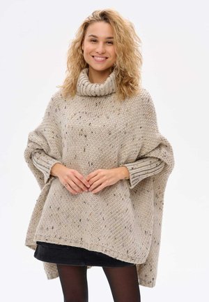 Beige gebreide poncho met een hoge kraag, versierd met textuur garen en meerkleurige vlekken. Losse, oversized pasvorm met ribgebreide mouwranden.