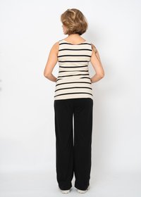 Gestreifter ärmelloser Top in Creme und Schwarz über schwarzen weiten Hosen, mit tailliertem Schnitt und weichem, dehnbarem Stoff.