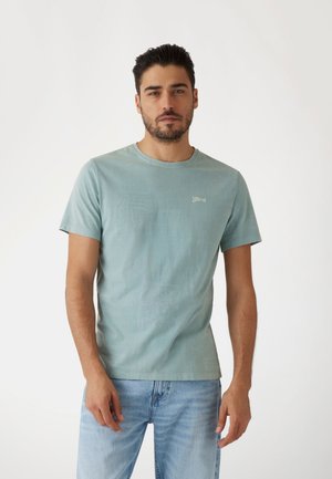 Camiseta de algodón azul claro con cuello redondo y mangas cortas. Presenta un logo sutil en el pecho y un acabado suave y texturizado.
