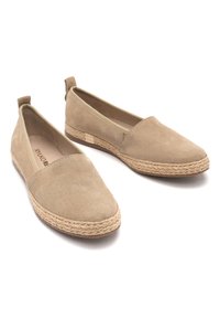 Beige suede slip-on shoes with jute rope detailing along the sole and a low profile. Features a smooth texture and minimalistic design.
