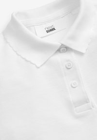 Chemise polo blanche en tissu texturé, dotée d'un col festonné, de trois boutons et d'une étiquette "next SCHOOL" à l'intérieur.