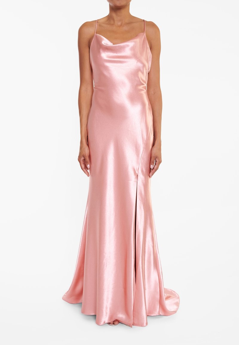 Robe en satin longue sans manches de couleur rose blush avec un col bénitier et une fente à l'avant, portée par une personne debout sur un fond uni.