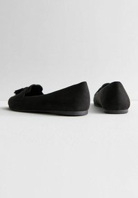 Zwarte suède ballerina's met een zachte textuur, voorzien van een strikaccent aan de voorkant en een laag profiel ontwerp met een gladde zool.