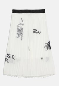 Valkoinen laskostettu hame mustalla kimallevyöllä, jossa on mustaa tiikeri-printtiä ja erilaisia graafisia kuvioita, mukaan lukien tähtiä ja laineita.