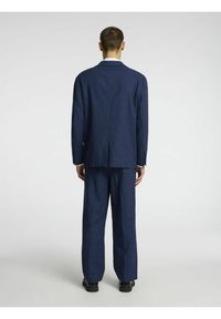 Costume bleu marine en tissu léger, comprenant un blazer ajusté et un pantalon assorti avec une texture lisse et un design minimaliste.