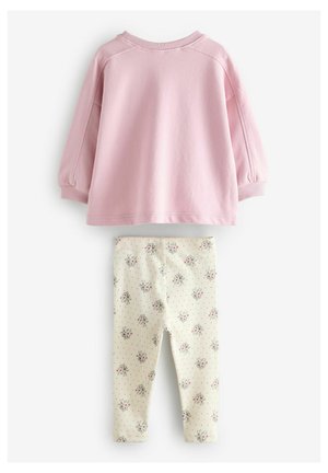 Sweatshirt en coton rose à manches longues, associé à un legging crème avec un petit motif floral et des accents de pois noirs.