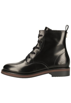 Bota de tobillo de cuero negro brillante con cordones en la parte delantera, ribete de suela marrón, lengüeta en el talón y pequeño parche con logotipo cerca del tobillo.