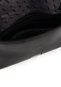 Černá texturovaná kožená kabelka s elegantním designem. Uvnitř má hladké černé podšívky s vlnkovými vzory a více přihrádek na karty.