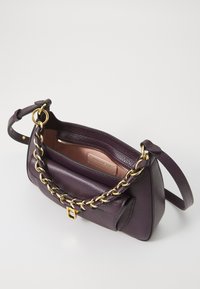 Purple leather handbag with a textured finish, gold chain accent, single strap, and a zippered interior pocket. Brand label visible inside.
