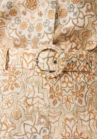 Tissu beige et marron à motif cachemire avec une ceinture assortie dotée d'une boucle ronde recouverte de tissu et d'œillets métalliques.
