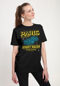 Černé tričko s krátkým rukávem a volným střihem, na kterém je žlutý a modrý grafický text s nápisem "PARIS Speed Demon" a ilustrací auta.