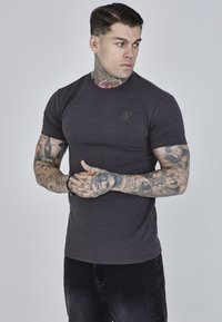 Donkergrijze aansluitende t-shirt met korte mouwen, geribde ronde hals en een klein geborduurd logo op de borst. Gemaakt van een gladde, rekbare stof.