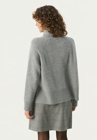 Lysegrå sweater med høj krave, ribstrikkede cuffs og kant. Blød tekstur, har en afslappet pasform og skrå sømdetaljer på skuldrene.