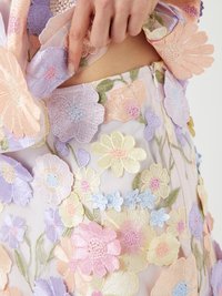 Stickad blomsterdesign på genomskinligt tyg; innehåller flerfärgade blommor i pastellnyanser, inklusive rosa, lila och gult.