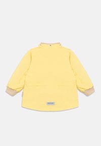 Κίτρινο μπουφάν με λεία υφή, ριμπ μανσέτες και κουμπώματα στο λαιμό. Διαθέτει μια μικρή ετικέτα με το λογότυπο στην πλάτη.
