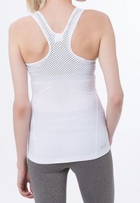 Débardeur de sport blanc à dos nageur, doté d'une texture perforée pour la respirabilité, associé à des leggings gris ajustés.
