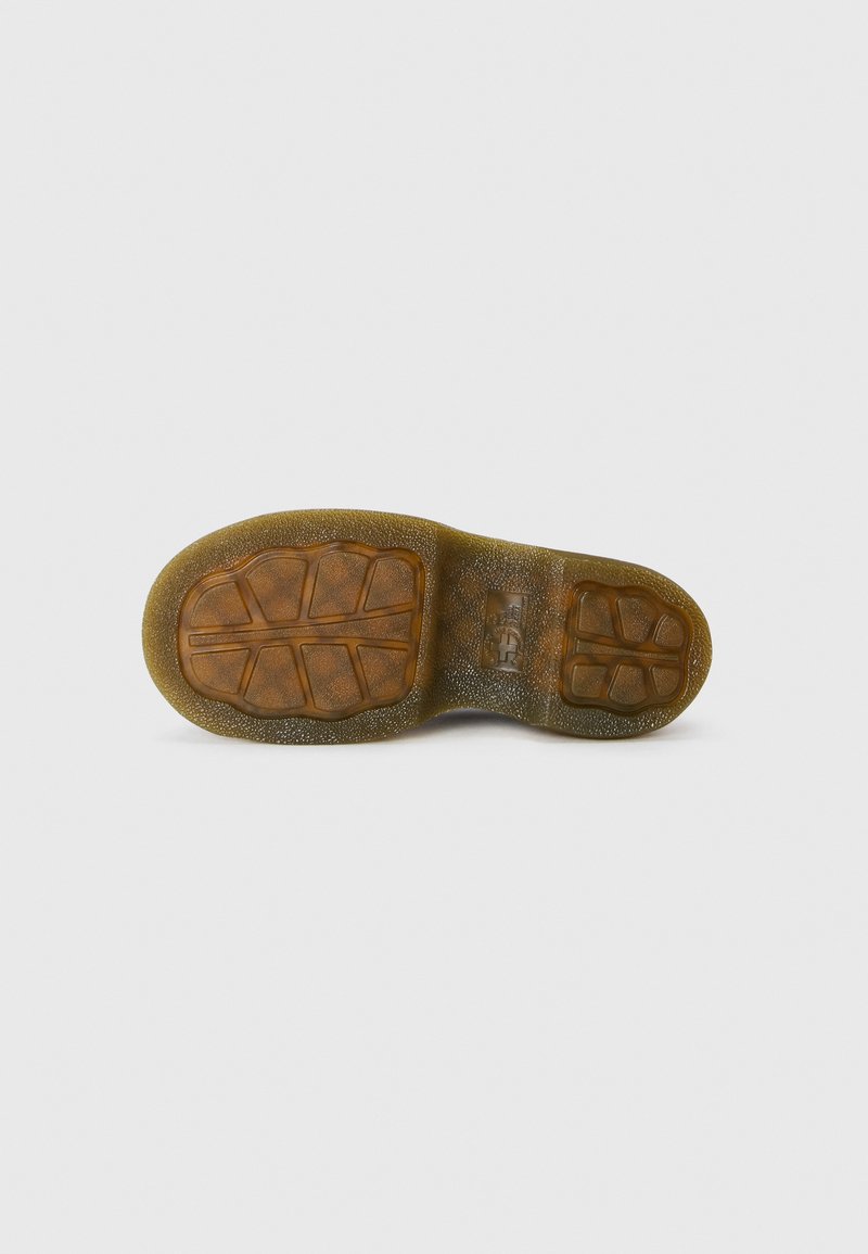 Semelle de chaussure en caoutchouc avec une surface texturée ; présente des motifs de grip irréguliers ; couleur marron avec une finition tachetée ; bords arrondis.