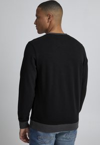 Schwarzer Sweatshirt mit Rundhalsausschnitt, mit gerippten Bündchen und Saum. Glatte Textur mit einem kontrastierenden grauen Band am Halsbereich.