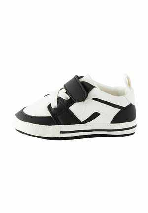 Baskets pour tout-petits blanches et noires avec lacets blancs, une bride en velcro noire et des bandes noires sur la semelle et les côtés.