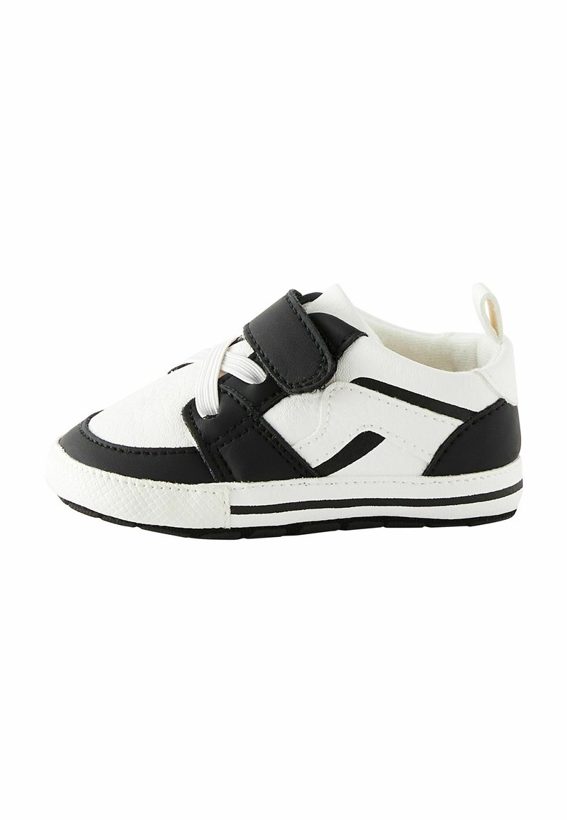 Baskets pour tout-petits blanches et noires avec lacets blancs, une bride en velcro noire et des bandes noires sur la semelle et les côtés.