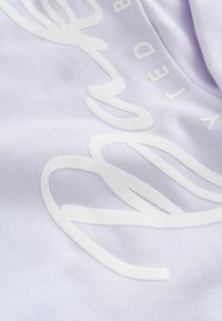 Lys lilla stof med blanke hvide bogstaver og bølgeformer. Strukturen er glat med en svag glans.