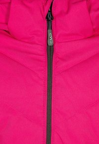 Giacca isolante rosa con zip nera e cuciture a zigzag. Il tessuto ha una superficie liscia e presenta un cappuccio funzionale.