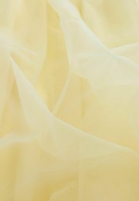 Permatomas geltonas audinys, turintis lengvą ir gaivų tekstūrą, su minkštais klostėmis ir švelniomis atspalvių variacijomis visame paviršiuje.