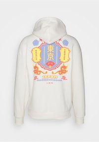 Vit kapuschong med en färgglad grafik på baksidan som innehåller japansk text, drakar och dekorativa kanter. Mjukt tyg och avslappnad passform.