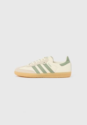 Sneaker Adidas Samba a profilo basso in crema con strisce e tallone verde oliva, suola in gomma color noce e punta in camoscio.