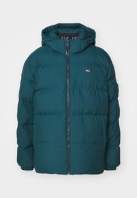 Teal-isolerad pufferjacka med huva, som har en framzipper och elastiska manschetter. Enkel design med horisontella quiltade sektioner och en logotypapplikation.