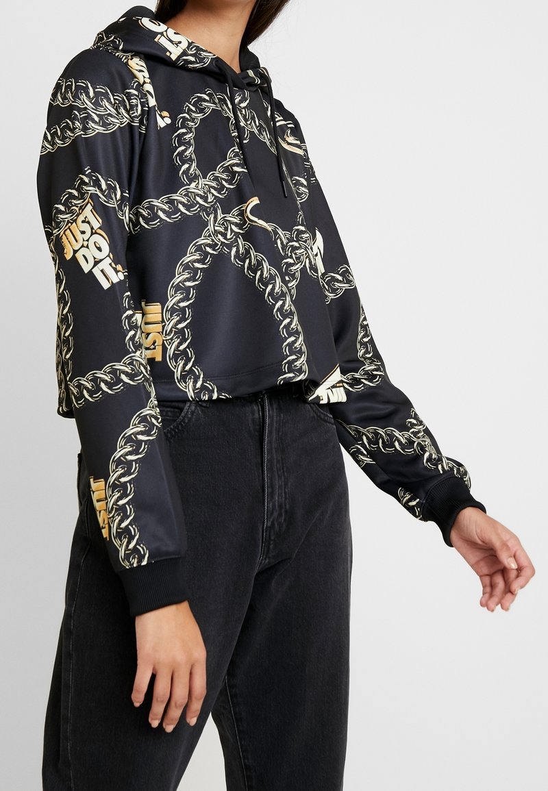 Cropped black hoodie with a chain pattern and gold accents. Features a drawstring hood and black ribbed cuffs. Distinct "JUST DO IT" text.