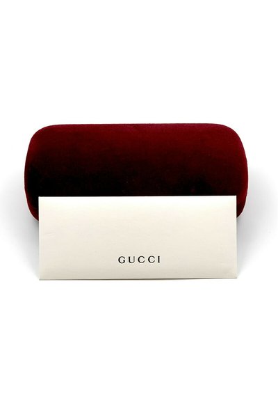 Custodia per occhiali in velluto rosso con bordi arrotondati, abbinata a un inserto in carta di colore crema con la scritta "GUCCI" stampata in nero.