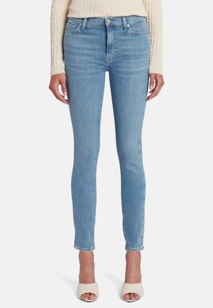 Jean skinny bleu clair en tissu denim, avec une taille haute, un design à cinq poches et des détails de décoloration subtils.