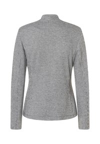 Zwarte en witte houndstooth-gepatroneerde blazer met een getailleerd ontwerp, lange mouwen en een hoge kraag, gemaakt van gestructureerde stof.