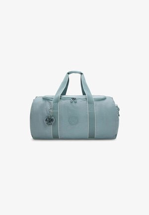 Light blue cylindrical duffel bag with dual handles, front zipper, logo patch, and a small plush keychain attached to one handle.