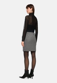 Black sheer long-sleeve top paired with a fitted patterned skirt and black ankle boots. Notable details include a high collar and textured fabric.