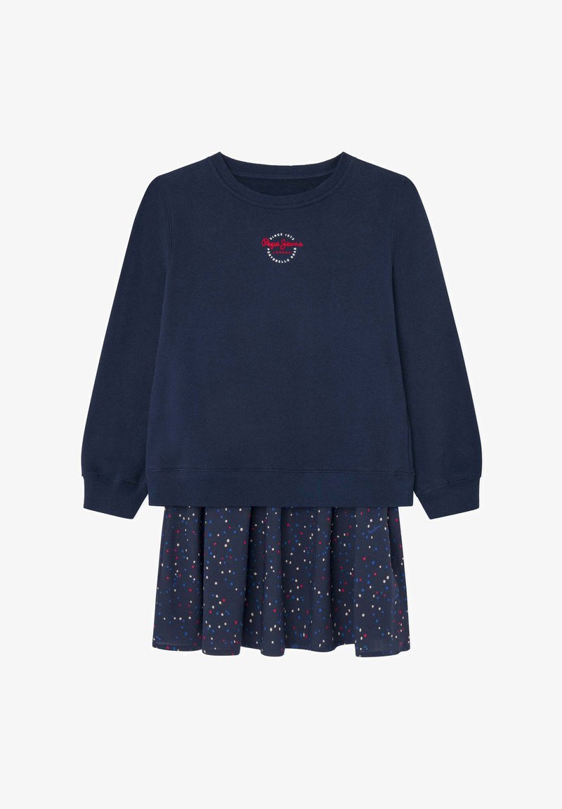 Sudadera navy de manga larga y cuello redondo, con un pequeño logo. Adjunto hay una falda plegada con un patrón de lunares en rojo, blanco y azul.