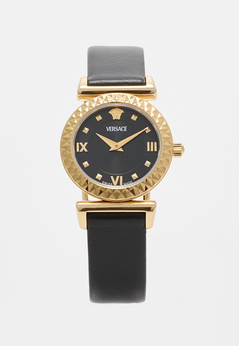 Montre Versace avec un boîtier rond en or, un cadran noir, des index horaires dorés et un bracelet en cuir noir. Présente une lunette et une couronne texturées.