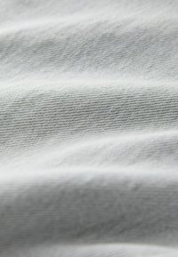 Lichtgrijze stof met een gladde textuur, voorzien van subtiele diagonale strepen. Het materiaal is zacht en licht gedrapeerd, wat zorgt voor zachte golven.