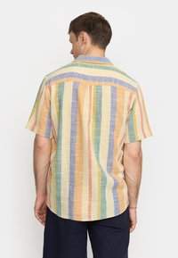 Korte mouw, multikleurige gestreepte shirt van lichtgewicht stof. Kenmerkt pastelkleuren van oranje, blauw, groen en crème, met een relaxte pasvorm.