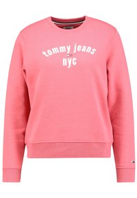 Rosa sweatshirt med rund hals, ribbade muddar och fåll, med "tommy jeans nyc" tryckt över bröstet i vitt. Mjukt bomullsblandat material.