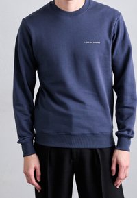 Felpa blu navy realizzata in tessuto morbido, con colletto rotondo e polsini a coste. Logo "Tiger of Sweden" in bianco sul petto.