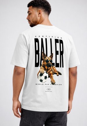 Man wearing a white t-shirt with a graphic of a German shepherd dog in sunglasses holding a soccer ball and text "Certified Baller, World Pup Champion."