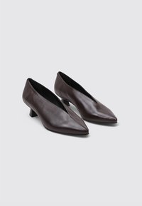 Zapatos de tacón de cuero marrón con un diseño de punta afilada, tacones delgados y una textura suave. Presentan un corte en forma de V en los laterales.