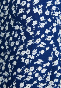 Marinblått tyg med liten vit blommönster, som har känsliga blommor och blad, vilket ger en texturerad känsla.