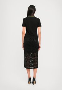 Black short-sleeve polo shirt with a yellow collar, paired with a black lace pencil skirt. The skirt features a floral pattern and is form-fitting.