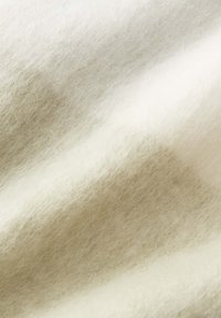 Tessuto di lana color crema, con una texture morbida e una leggera lucentezza, presenta un delicato motivo a gradiente e spessori variabili.