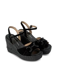Sandali con tacco a cuneo neri in suede, con punta aperta, fascette alla caviglia e decorazioni ornate. Piattaforma intrecciata testurizzata per stabilità.